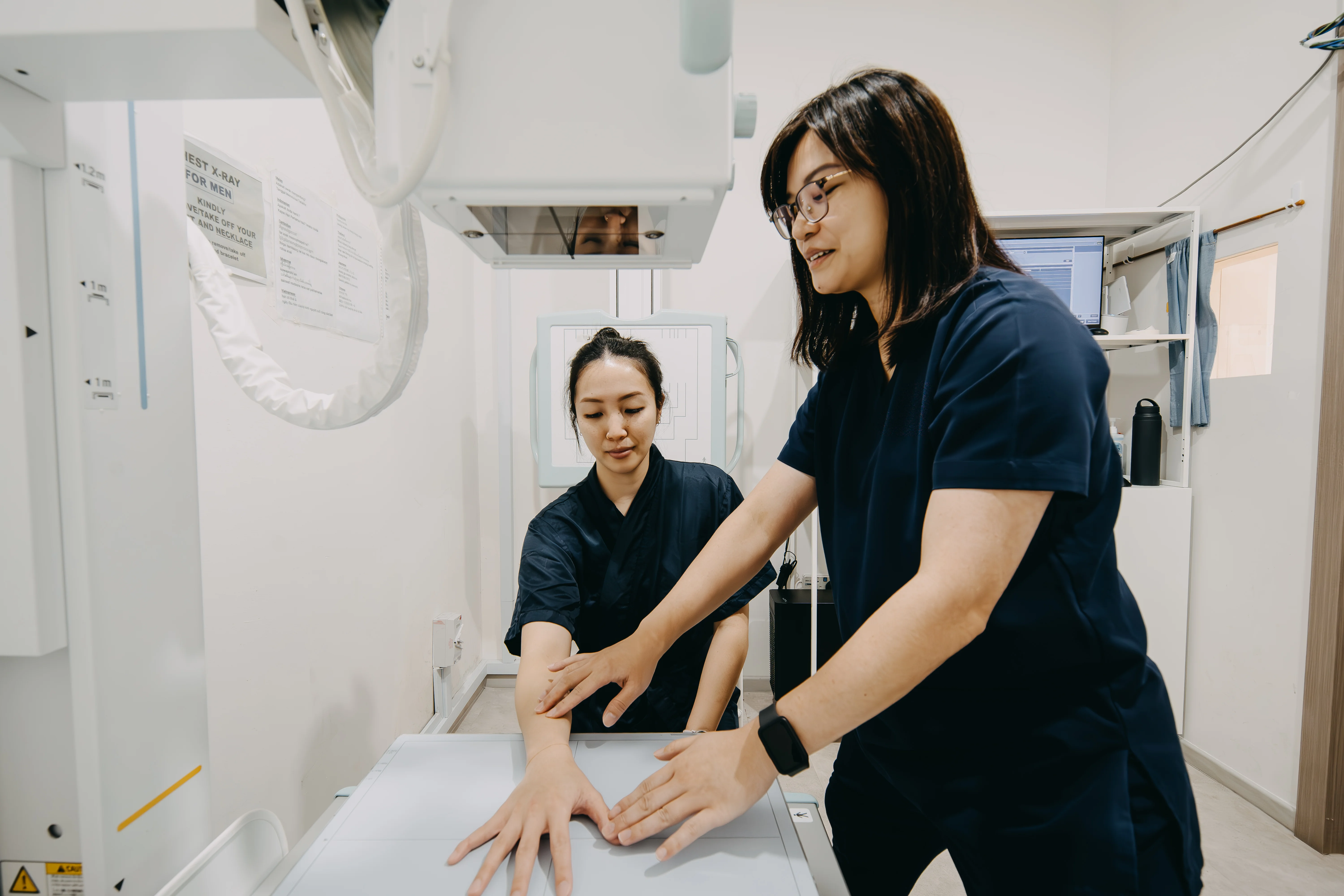 Radiographer positioning patient's hand for an X-ray at Singapore Women's Clinic