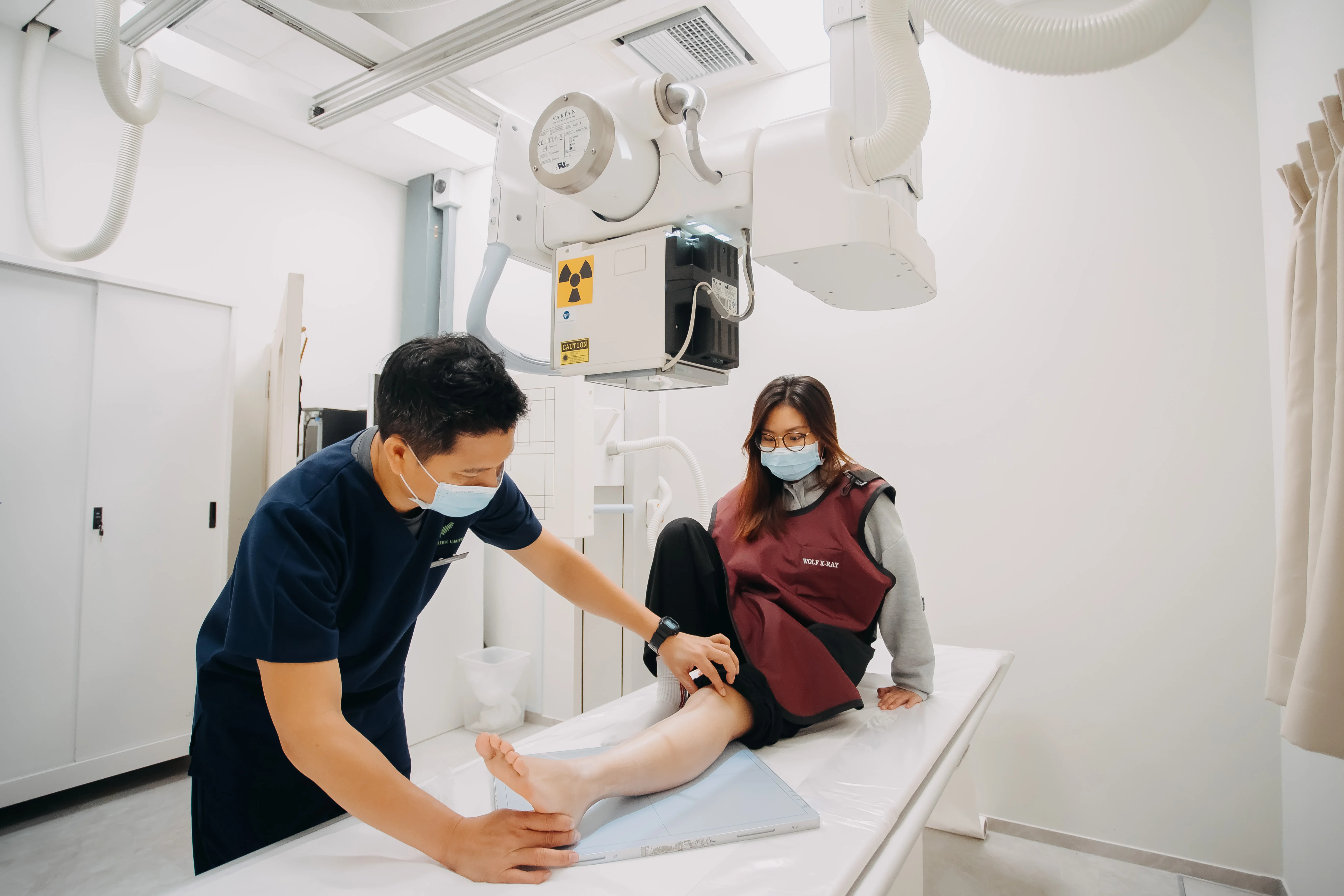 Radiographer positioning patient for a knee X-ray scan at Singapore Women's Clinic