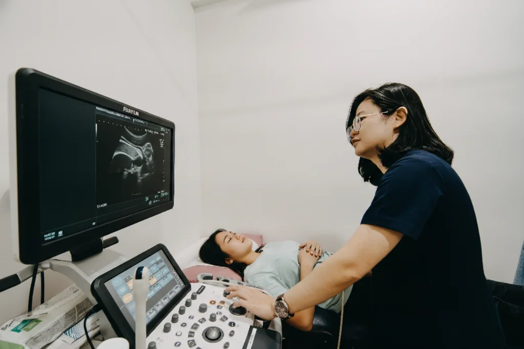 Clinic staff performing an abdominal ultrasound scan on a female patient