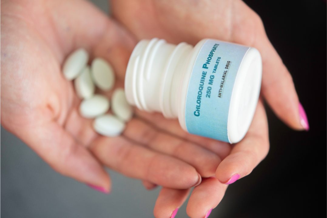 Person holding chloroquine phosphate tablets used as anti-malarial medication for prophylaxis.