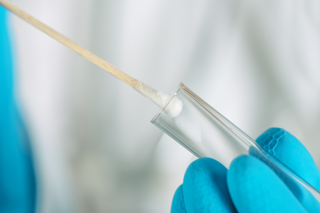 Close up of medical swab sample being inserted into test tube for trichomoniasis testing in clinic.