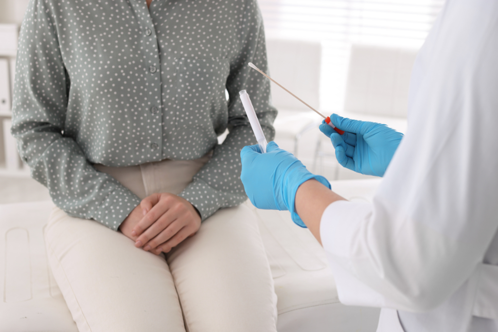 Doctor holding swab in front of seated female patient during chlamydia swab test preparation.