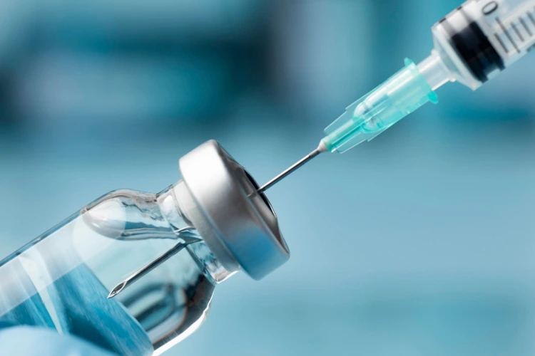 Syringe drawing vaccine from vial, illustrating shingles vaccine dosage and intramuscular injection.